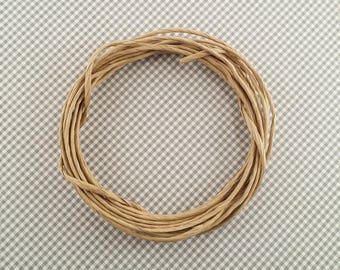 May include: A close-up of a brown paper twine wound into a circle on a gray and white checkered surface.