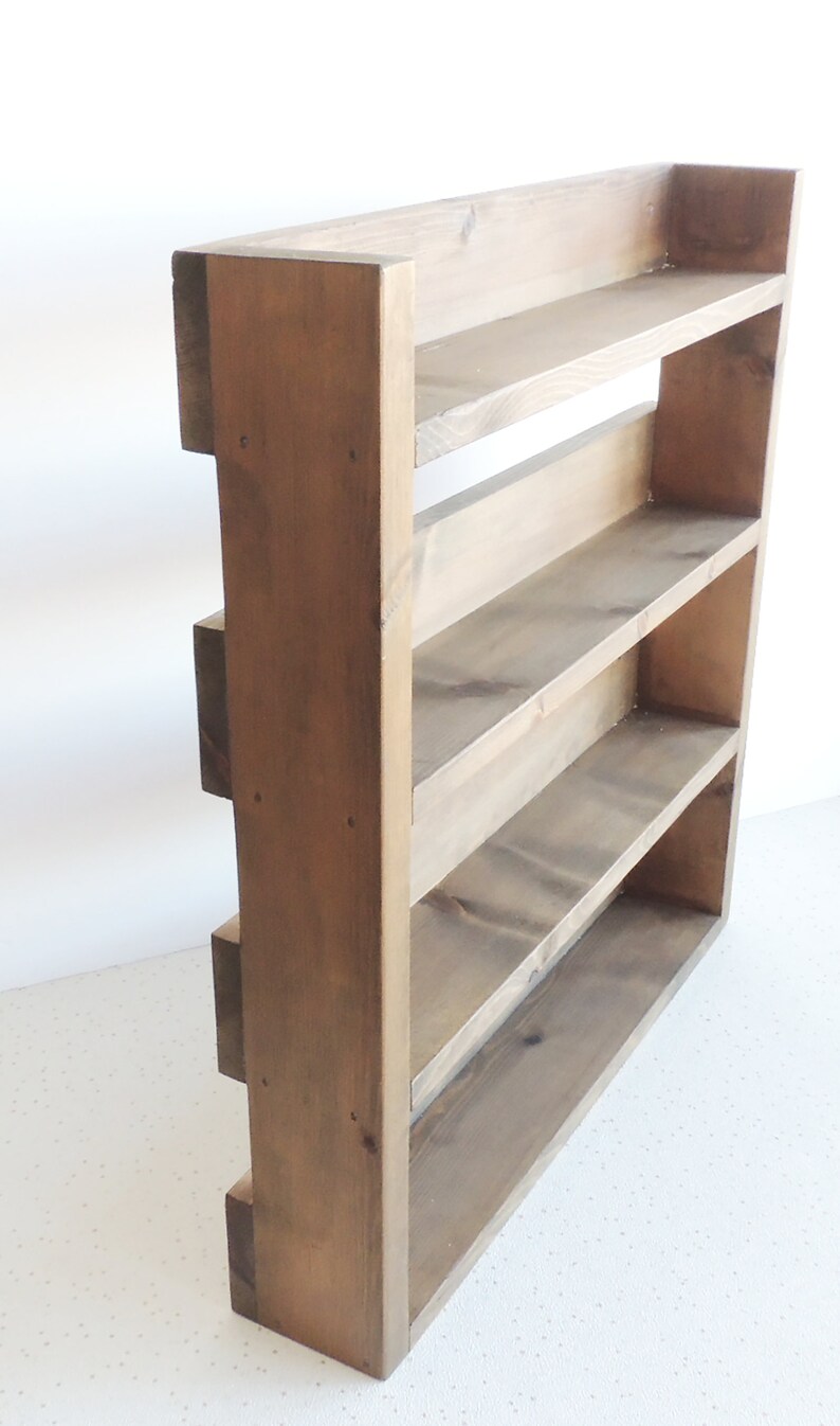 May include: A rustic wooden shelf unit with four shelves. The shelf is made of natural wood with a dark brown stain. The shelf is freestanding and has a rectangular shape.