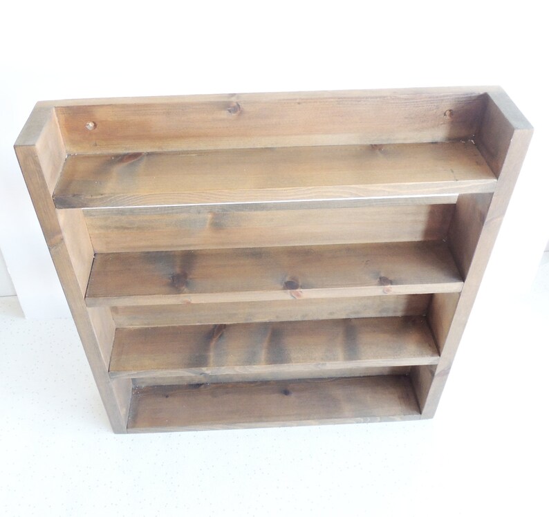 May include: A rustic wooden shelf unit with four shelves. The shelf is made of natural wood with a brown stain. The shelf is mounted on a wall.
