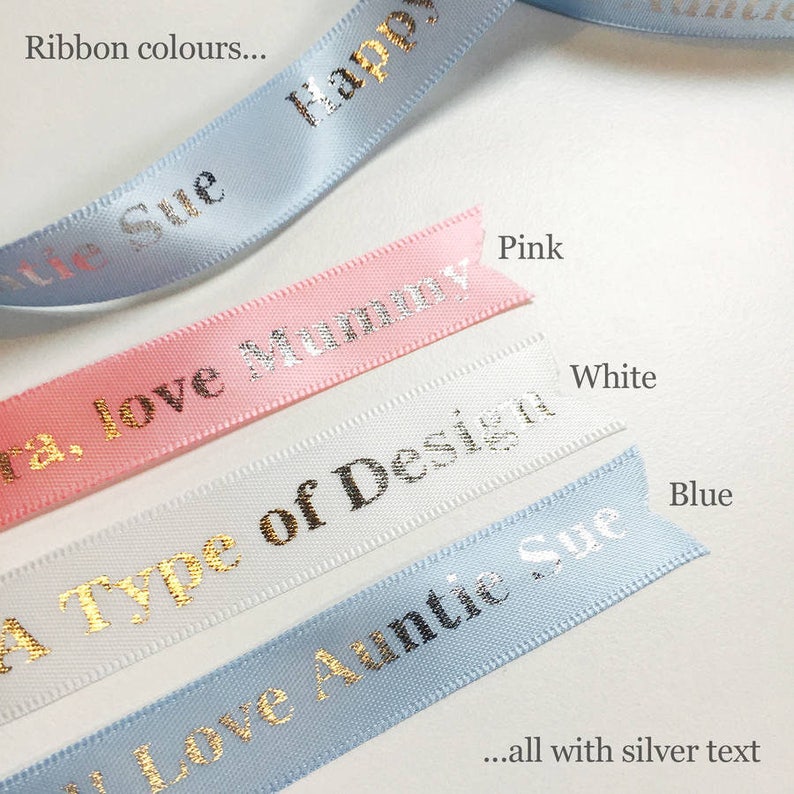 K&ouml;nnte beinhalten: Nahaufnahme von farbigen B&auml;ndern mit silbernem Text. Die B&auml;nder sind in verschiedenen Farben wie Rosa, Wei&szlig; und Blau gehalten und tragen Aufschriften wie "Happy" und "Love Mummy". Das Bild enth&auml;lt auch den Text "Ribbon colours..." und "...all with silver text."