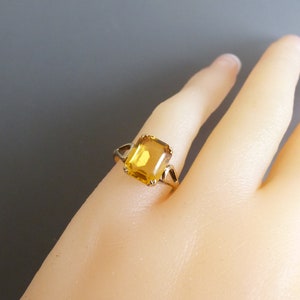 May include: A gold ring with a large, square-shaped, yellow gemstone.