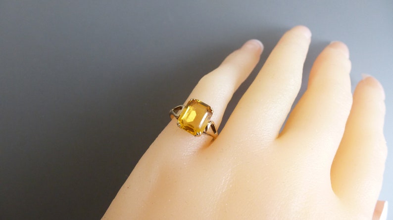 May include: A gold ring with a large, square-shaped, yellow gemstone.