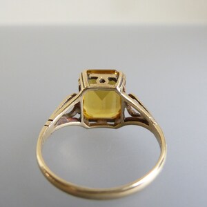 May include: A gold ring with a yellow gemstone set in a delicate filigree design.