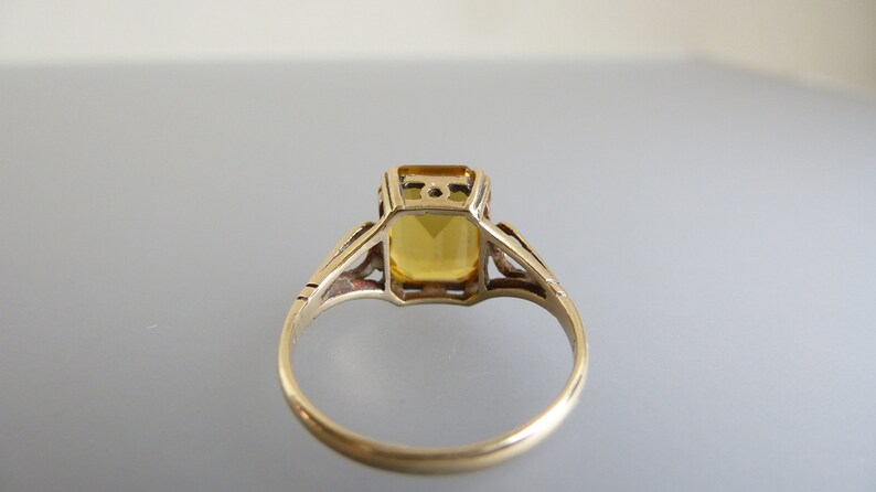 May include: A gold ring with a yellow gemstone set in a delicate filigree design.