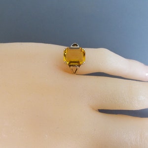 May include: A gold ring with a large, square, yellow gemstone.