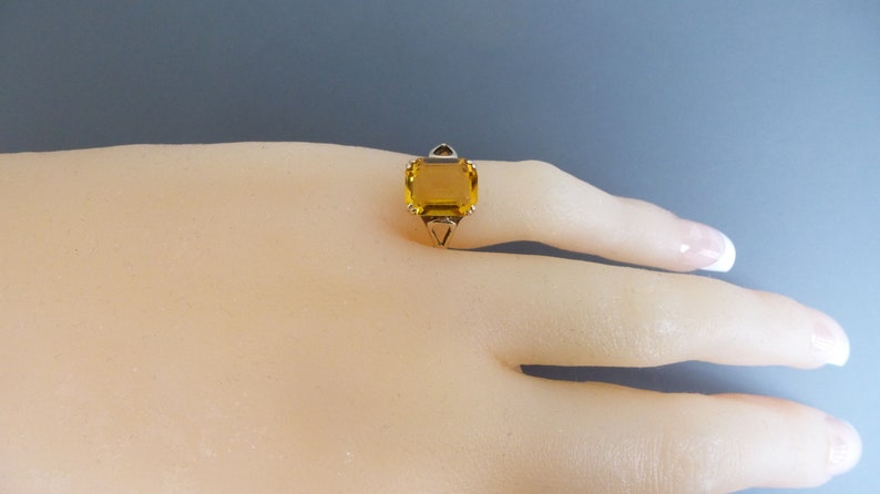 May include: A gold ring with a large, square, yellow gemstone.