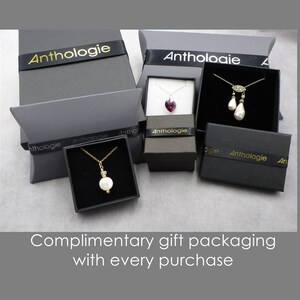 Puede incluir: Tres cajas de joyer&iacute;a con la etiqueta Anthologie que contienen collares con un colgante de perla blanca en cadena dorada, un colgante de coraz&oacute;n morado oscuro en cadena plateada y dos perlas blancas en cadena plateada. Texto: Complimentary gift packaging with every purchase.