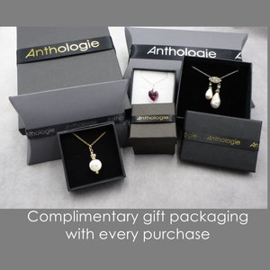 May include: Four black gift boxes with gold lettering that reads "Anthologie" on the ribbon. The boxes contain various jewelry items, including necklaces with pearls, a heart-shaped pendant, and a teardrop pendant.