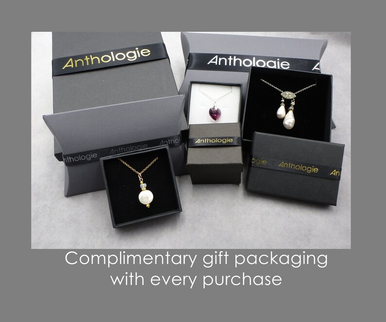 May include: Four black gift boxes with gold lettering that reads "Anthologie" on the ribbon. The boxes contain various jewelry items, including necklaces with pearls, a heart-shaped pendant, and a teardrop pendant.