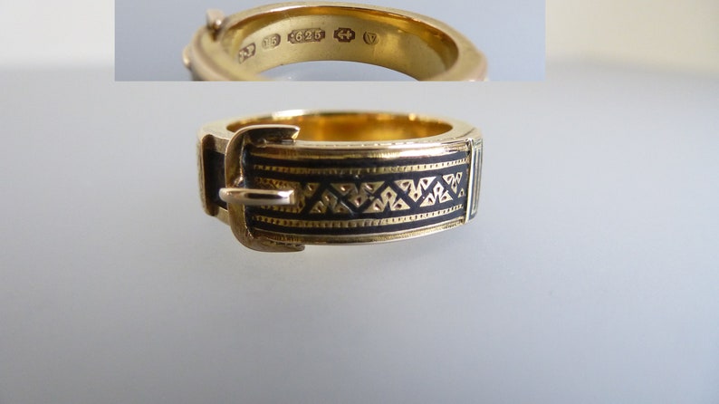 Puede incluir: Un anillo de oro dise&ntilde;ado para parecer un cintur&oacute;n con hebilla, con una incrustaci&oacute;n de esmalte negro con un patr&oacute;n geom&eacute;trico repetitivo. El interior de la banda muestra marcas claras, incluido el n&uacute;mero 625, que indica su composici&oacute;n.