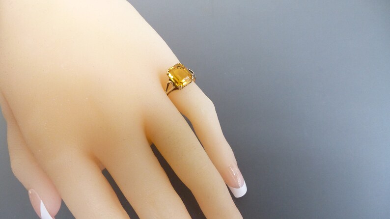 May include: A gold ring with a large, square-shaped, yellow gemstone.