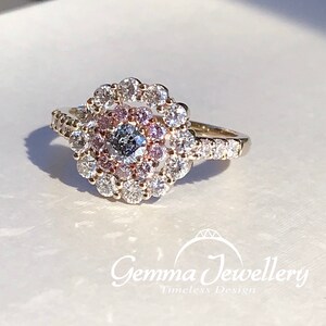 May include: A gold ring with a large center diamond surrounded by a halo of smaller diamonds. The halo is set with pink diamonds.