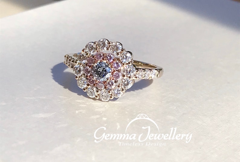May include: A gold ring with a large center diamond surrounded by a halo of smaller diamonds. The halo is set with pink diamonds.