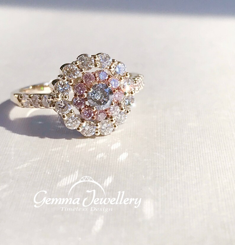 May include: A gold ring with a center diamond surrounded by a halo of smaller diamonds. The halo is set with pink diamonds in a swirling pattern.