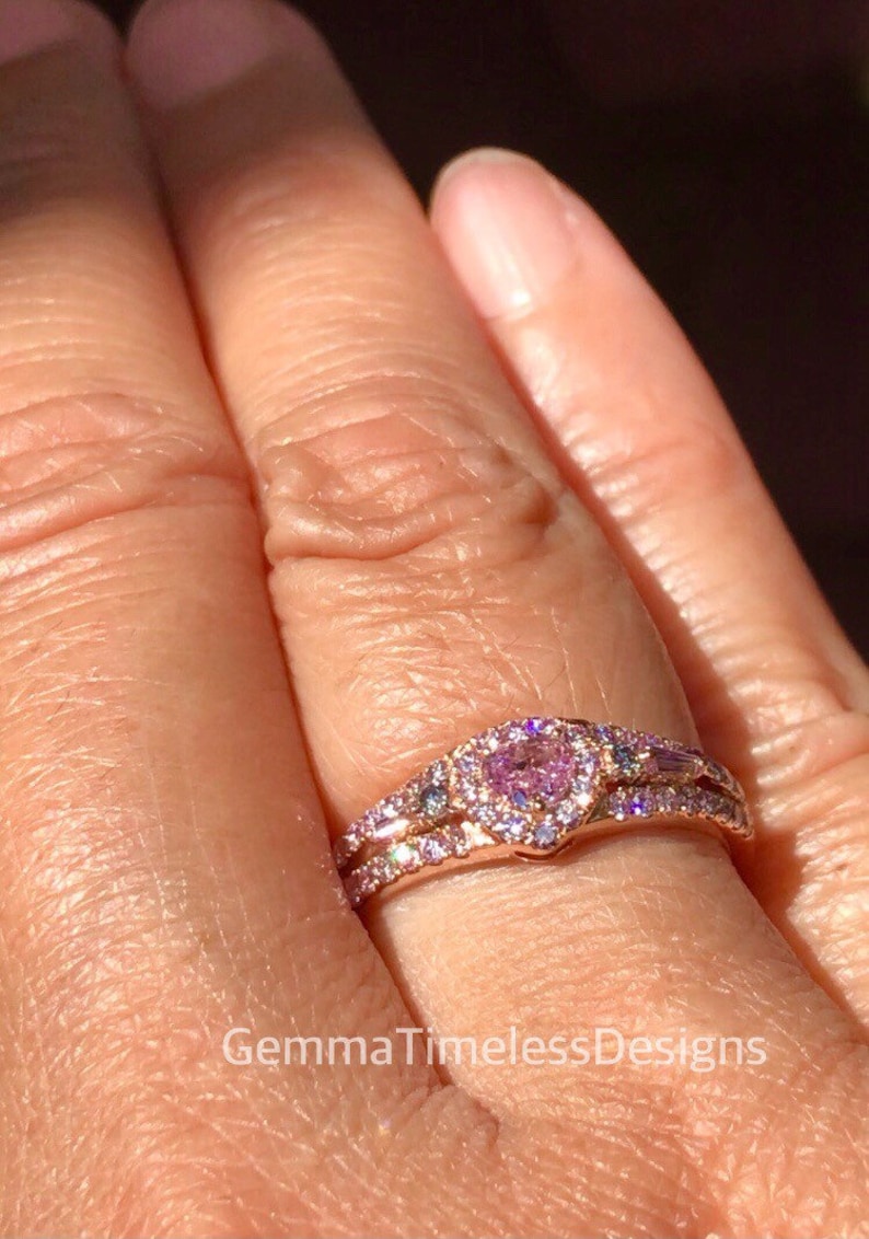 May include: A rose gold ring set with a heart-shaped pink gemstone surrounded by smaller diamonds. The ring is on a finger.