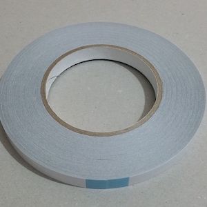 May include: A roll of double-sided adhesive tape with a light blue backing.