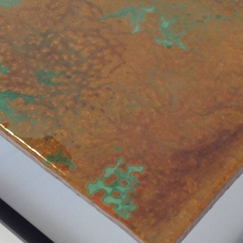 May include: Close-up of a copper surface with a green patina. The surface has a textured, hammered look and is slightly glossy.
