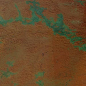 May include: An aerial view of a landscape with a large area of green vegetation surrounded by a brown, dry area.