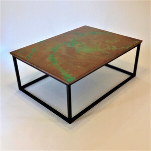 May include: A modern coffee table with a black metal frame and a copper top with green accents.