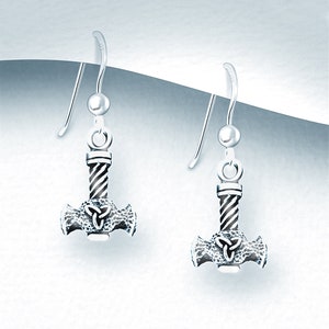 May include: A pair of silver-colored earrings featuring a hammer design. The hammer has a twisted handle and a textured head with a Celtic knot design. The earrings have a hook closure.
