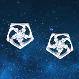 May include: A pair of silver-toned stud earrings, each featuring a pentagonal frame with a central cluster of five small, clear, round-cut stones arranged in a floral pattern. The metal has a polished finish, and the design creates an openwork effect.