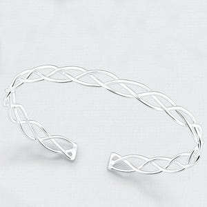 May include: A silver-colored open cuff bracelet with a Celtic knot design. The bracelet features an intricate interwoven pattern, creating a continuous, flowing design. The ends of the bracelet are open, allowing for easy wear. The bracelet is displayed against a white background.