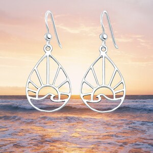 May include: A pair of silver dangle earrings with a sun and wave design. The earrings are shaped like teardrops and have a delicate, openwork design.