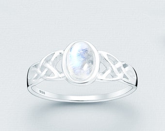 May include: A silver ring with a Celtic knot design and a white moonstone oval gemstone. The ring is marked "925" on the inside band.