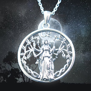 May include: Silver pendant necklace featuring a detailed depiction of a goddess standing within a tree of life design. The pendant is circular and has a delicate, intricate design.