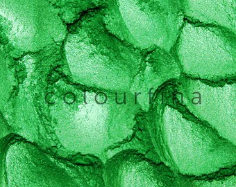 May include: Close-up of a green eyeshadow with a shimmery finish. The eyeshadow is in a pressed powder form and has a textured surface.
