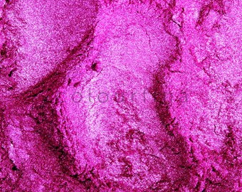 May include: Close-up of a vibrant magenta eyeshadow with a shimmery, glittery texture. The eyeshadow is finely milled and has a smooth, velvety finish.