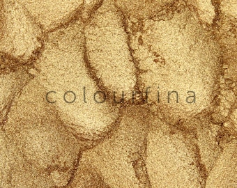 May include: Close-up of a gold metallic eyeshadow with a shimmery finish. The texture is smooth and appears to be finely milled.