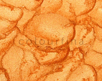 May include: Close-up of a metallic orange powder with a shimmery finish. The powder has a textured, almost bubbly appearance.