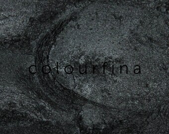 May include: Close-up of a dark gray metallic powder with a subtle shimmer. The powder is textured and has a slightly rough surface.