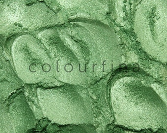 May include: Close-up of a textured, green eyeshadow with a metallic sheen. The word "colourfina" is subtly printed across the surface. The eyeshadow appears to be pressed into a pattern of overlapping shapes.