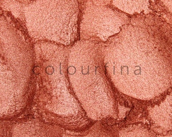 May include: Close-up of a shimmery, metallic copper eyeshadow. The texture is smooth and finely milled, with a subtle sparkle.