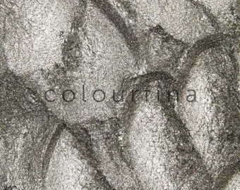 May include: Close-up of a silver metallic eyeshadow with a textured, grainy finish.