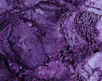 May include: Close-up of a purple eyeshadow powder with a textured surface.