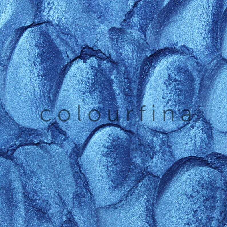 May include: Close-up of a blue metallic eyeshadow with a textured surface. The word "colourfina" is printed on the eyeshadow.