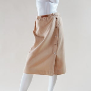 1970s Courrèges wrap skirt tan beige vintage designer knee length skirt with silver buttons and leather nameplate logo at waist image 1