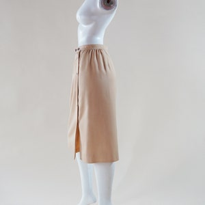 1970s Courrèges wrap skirt tan beige vintage designer knee length skirt with silver buttons and leather nameplate logo at waist image 3