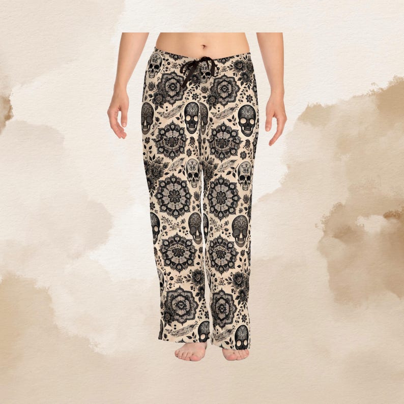 Puede incluir: Pantalones de pijama color crema con un estampado floral y calaveras en negro. Los pantalones tienen cintura con cord&oacute;n y un ajuste relajado. El dise&ntilde;o incluye calaveras estilizadas, flores y otros elementos decorativos.