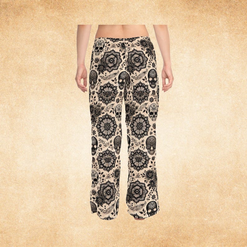 Puede incluir: Pantalones palazzo color crema con un estampado de calaveras y flores en negro. Los pantalones de pernera ancha presentan un dise&ntilde;o repetido de calaveras, flores y elementos ornamentales. Los pantalones son de tejido ligero.