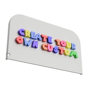 May include: A white sign with rounded corners features the text "CREATE YOUR OWN CUSTOM" in colorful, 3D block letters. The letters are in various colors, including yellow, blue, red, and green.