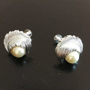 Puede incluir: Un par de pendientes de tono plateado con un acento de perla. Los pendientes presentan un diseño de hojas superpuestas.