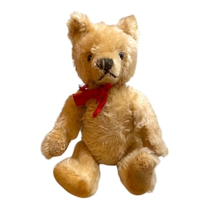 May include: A vintage, cream-colored teddy bear with a red bow tie. The bear is sitting with its legs crossed and has a worn, well-loved appearance.