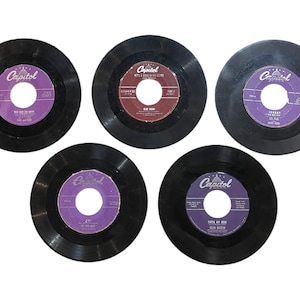 May include: Five vintage vinyl records with black discs and colorful labels. The labels feature text and the Capitol Records logo. The records are arranged in a circular pattern, showcasing their classic design and musical heritage.