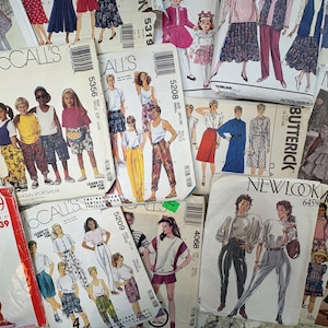 May include: A collection of vintage sewing patterns from brands like McCall's, Butterick, and New Look. The patterns feature illustrations of clothing designs for adults and children, with various styles and sizes. The patterns are in various colors.
