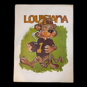 May include: A vintage print featuring a cartoon tiger mascot wearing a football uniform and helmet with the letters "LSU" on it. The mascot is running with a football in its hand. The print has the word "LOUISIANA" at the top.
