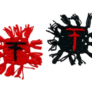 May include: Two crocheted squares with fringe, one red and one black, each with a black and red "T" in the center.